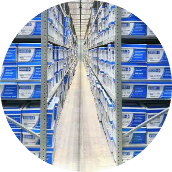 The hand of a person holding a scanner and pointing it at the barcode on the end of an archive box on a shelf