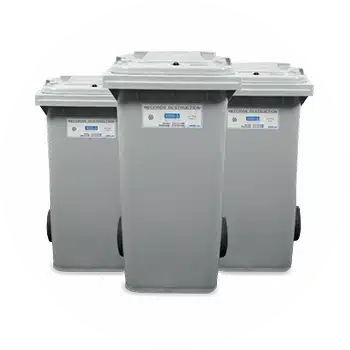 The hand of a person holding a scanner and pointing it at the barcode on the end of an archive box on a shelf